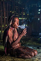 Dani tribe woman smoking inside home, Budaya village, Suroba, Trikora Mountains, West Papua, Indonesia. March 2018.