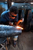 Deaf worker, in metal factory, making metal artefacts for tourist industry, Antananarivo, Madagascar. October 2018.