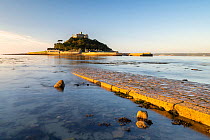 St Michael's Mount in morning light, cobbled causeway underwater at high tide. Marazion, Cornwall, England, UK. October 2020.