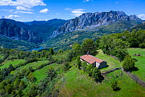 Aerial view of Chapel of Santa Maria surrounded by European yew (Taxus baccata) and mountains in distance, Las Ubinas-La Mesa Natural Park. Asturias. Spain. August 2020.