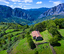Aerial view of Chapel of Santa Mara surrounded by European yew (Taxus baccata) and mountains in distance, Las Ubinas-La Mesa Natural Park. Asturias. Spain. August 2020.