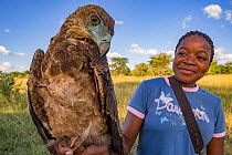 Young Mozambican scientist Diolinda Mundoza admires a juvenile bateleur eagle (Terathopius ecaudatus) that she just captured at a goat carcass in Gorongosa National Park, Mozambique. Editorial use onl...