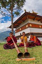 Buddhist monks playing Dungchen trumpet, Chime Lhakhang Temple (The &#39;fertility temple&#39;). Bhutan. September 2013. EDITORIAL USE ONLY.