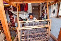 A woman weaving on a loom in Peguche, a village of weavers near Otavalo, Ecuador. Editorial use only.
