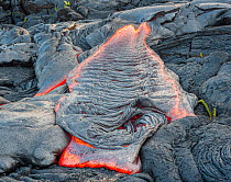 Molten lava streaming across solidified lava from Kilauea, Volcanoes National Park, Big Island, Hawaii.