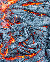 Molten lava streaming across solidified lava from Kilauea, Volcanoes National Park, Big Island, Hawaii.