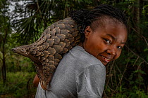 Mozambican wildlife veterinarian Mercia Angela  on her daily walk with Boogli, a female Cape pangolin  confiscated as  infant by Gorongosa&#39;s law enforcement team. Boogli&#39;s mother had already b...
