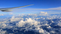 View out of a plane window looking at clouds and plane wing flying to Paris, France.