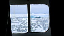 Looking out of a cabin window on an expedition cruise ship onto sea ice in the Lemaire channel between Booth Island and the Kiev Peninsular, Antarctica.