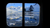 Looking out of a cabin window on an expedition cruise ship onto the Lemaire channel between Booth Island and the Kiev Peninsular, Antarctica.