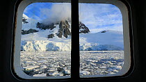 Looking out of a cabin window on an expedition cruise ship onto the Lemaire channel between Booth Island and the Kiev Peninsular, Antarctica.