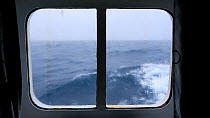 Waves moving outside a cabin window on an expedition cruise ship crossing the Drake Passage between Antarctica and South America.