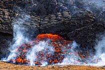 Edge of the lava field at the Fagradalsfjall volcano with a new flow of lava emerging from under the solidified lava. Fagradalsfjall, Iceland. 5 April 2021.