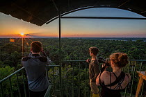 Students watch the sun set over the Amazon Rainforest, on the top of the viewing tower at Napo Cultural Center Lodge, Yasuni National Park, Ecuador.