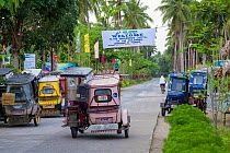 Street with motorcycle taxis and a whale shark banner over head, in Donsol, Sorsogon Province, Luzon, Philippines.