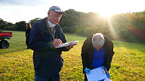 Volunteers recording data while a vaccinator inoculates a European badger (Meles meles) against TB. North Somerset, UK.