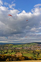 Paragliders flying from Selsley Hill, with Stroud and Gloucester in the background, Gloucestershire, UK, October.