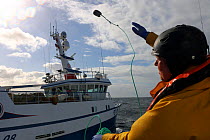 Crewman throwing heaving line during pair trawling operations. North Sea, March.