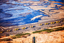 Massive dump trucks queuing to load with tar sand in front of a toxic wasteland. Syncrude mine, Athabasca, Alberta, Canada, 2012
