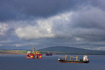 Bulk carrier and oil rigs in Scapa Flow, Orkney Isles, Scotland. October 2020.