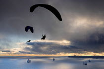 Paragliders flying over the the cruise ships anchored in Weymouth Bay, with Portland beyond, Dorset, England, UK. November 2020.