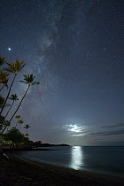 Moon shining through clouds, reflected on ocean, with Milky Way above. Anaeho&#39;omalu Bay, South Kohala, Hawaii, October, 2020.