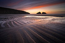 Holywell Bay at low tide, ripples and reflections at sunset, looking towards Carter&#39;s Rocks, Holywell Bay, near Newquay, Cornwall, UK. March 2021.