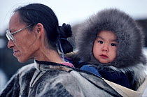 Inuit grandmother, Patdlunguaq,carring Peter in a sealskin Amaut (hooded jacket). Qeqertat, Northwest Greenland. (1980)