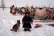 Pudako Serotetto, a young Nenets boy, standing by a corral with a young Laika reindeer herding dog on the spring migration. Yamal Peninsula, Siberia, Russia, 1996.
