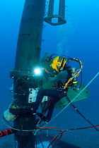 A commercial hard hat diver welding a fitting onto section of a wave energy buoy underwater, North Pacific Ocean, off Oahu, Hawaii. Model released.