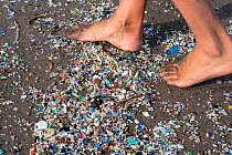 Person walking over plastic and microplastics covering the beach, brought in by the winds and the tides, Canary Islands.