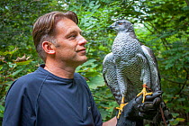 Naturalist and presenter Chris Packham with Ellie, a trained Northern goshawk (Accipiter gentilis), during filming for BBC programme &#39;Animals Guide to Britain&#39;, 2010.