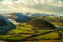 The Back Brook glacial and meltwater valley, Hanter Hill, Worsell Wood, viewed from Bradnor Hill. Snow-capped hills of the Radnor Forest in the background, Radnorshire/Herefordshire border, UK. Januar...