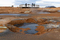 Tourists on a platform viewing mudpot in Namafjall or Hverir Geothermal Area, Northeast Iceland. May 2021.