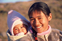 Tukumeq Qaerngaq, an Inuit mother, carrying her daughter, Maria, in a sealskin amaut (hooded jacket). Qingmiunaqarfik Island, Northwest Greenland, 1985.