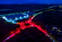 Street lights switched on at roundabout outside Worcester, England, showing that bulbs have been changed to red. October.