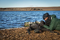 Ugo Mellone photographing hooded grebes on lake, Buenos Aires plateau, Patagonia National Park, Santa Cruz, Argentina.