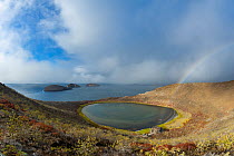 Saline lake in volcanic tuff cone crater, with rainbow, Bainbridge Islets, Galapagos, South America. October, 2020.