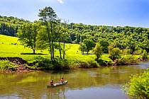 Two people in a Canadian canoe on the River Wye below Coppet Hill, Gloucestershire, UK. June, 2021.