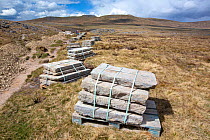 Stone slabs  used for repair work, piled up along the extremely popular Three Peaks footpath, Ingleborough, Yorkshire Dales National park, Yorkshire, UK. April, 2021.