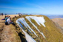 Crowd of visitors on the summit of Helvellyn, Lake District National Park, Cumbria, UK. April, 2021.