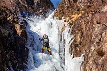 Ice climber climbing the frozen Low Water Beck waterfall, Lake District National Park, Cumbria, UK. February, 2021.