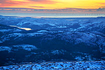 Sunset view over Coniston Water towards the coast and the Walney offshore wind farm from Red Screes, Lake District National Park, Cumbria, UK. January, 2021.