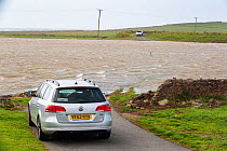 Cars stranded on coastal road cut off by storm surge flooding, Walney Island, Cumbria, Irish Sea, UK. August, 2020.