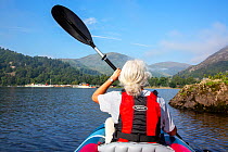 A woman paddling in an inflatable canoe, Ullswater, Lake District National Park, Cumbria, UK. August, 2020.