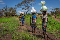 Women from Micheu community returning home with emergency food parcels distributed by the  park, after Cyclone Idai. Outskirts of Gorongosa National Park, Mozambique.  March 2019.
