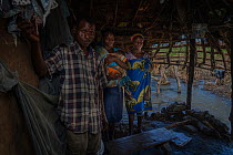 Teacher Ana Jo at home with her sister and their father, Jo Jimo (45), farmer and pastor, after Cyclone Idai. Outskirts of Gorongosa National Park, Mozambique. March 2019.