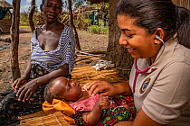 Nurse Berta Barros examining baby Rosalina's heart with her mother behind. Rosalina was born during Cyclone Idai. Outskirts of Gorongosa National Park, Mozambique. April 2019.