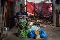 Aminha Vasco (49) in her home with food kit that she received from the park after Cyclone Idai. Outskirts of Gorongosa National Park, Mozambique. March 2019.