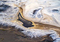 Aerial view after sunrise, showing the sun reflecting off water that has flowed into Lake Eyre South and formed a pond; the water being the result of recent uncommonly high local desert rainfall. Salt...